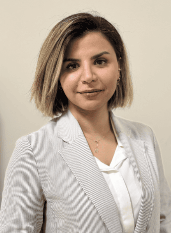 The image is of physiotherapist Atefe Ashrafi. She has shoulder length streaked hair and is wearing a beige blazer. 